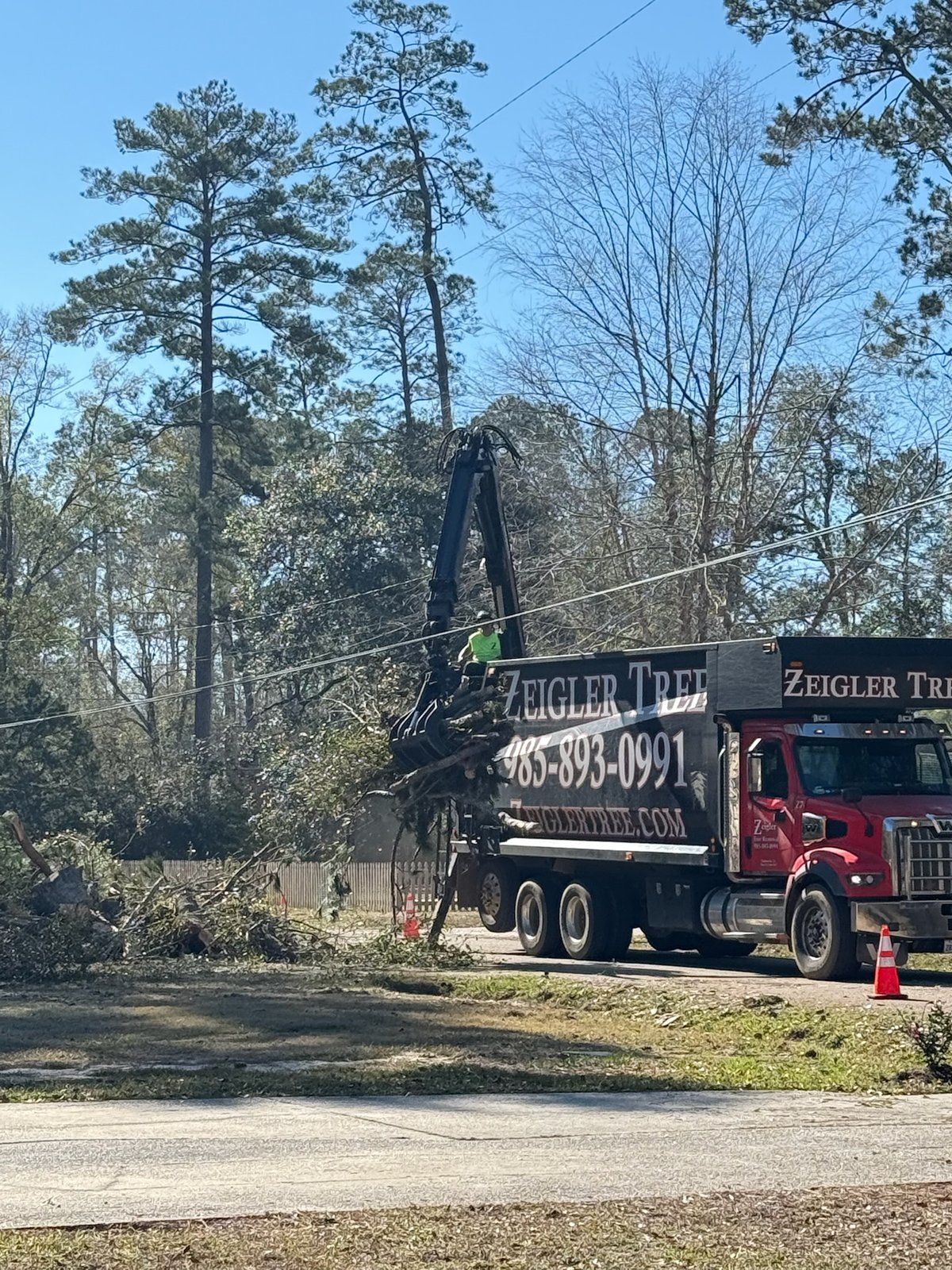 Grapple truck loading cut tree debris roadside