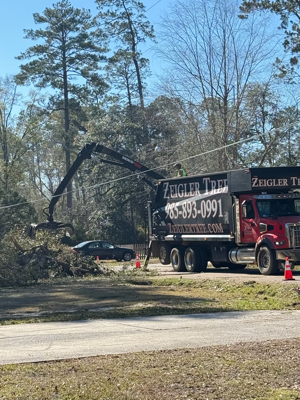 Grapple truck clearing storm debris along a residential street