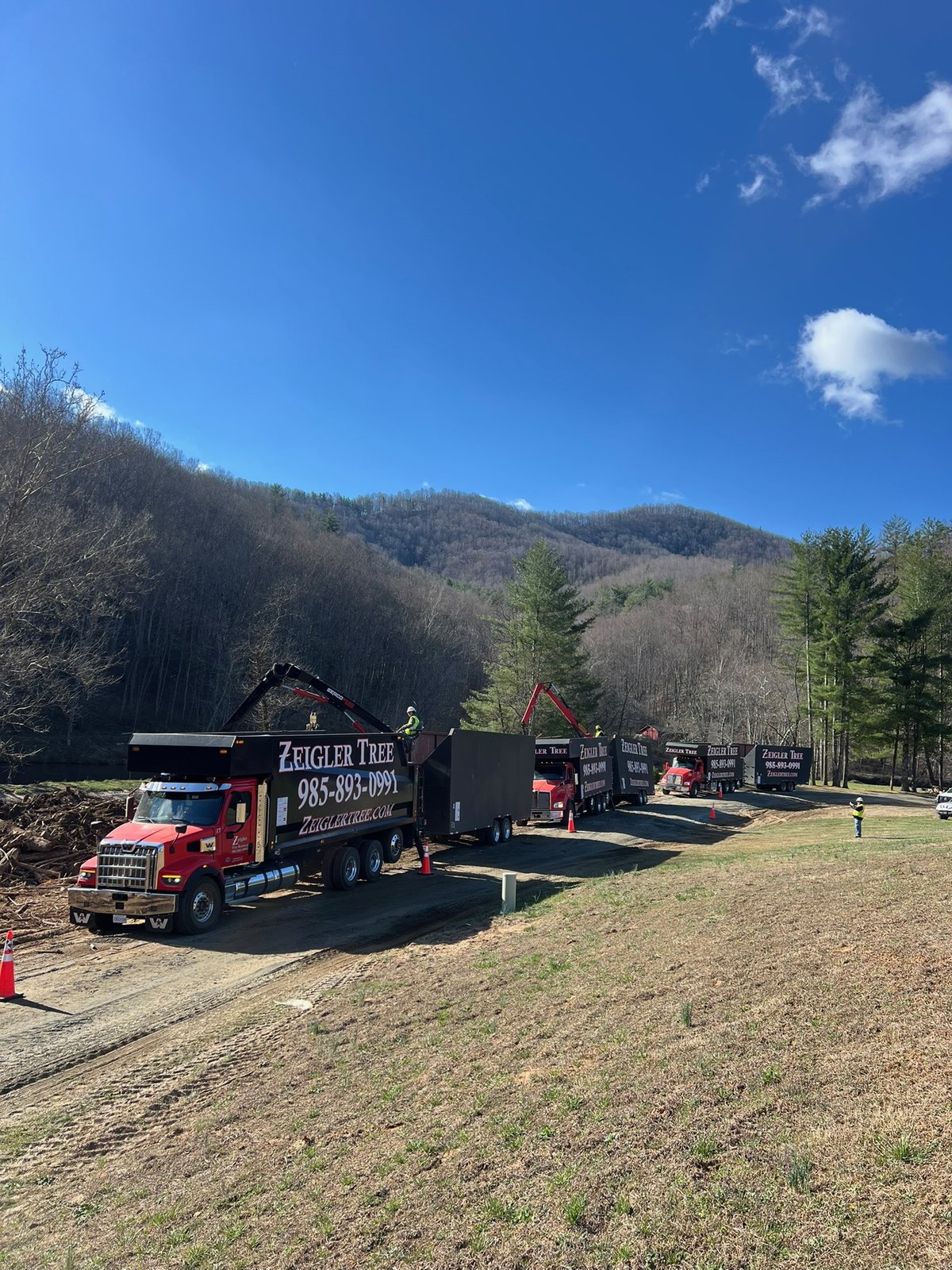A line of branded trucks staged along a job-site access road